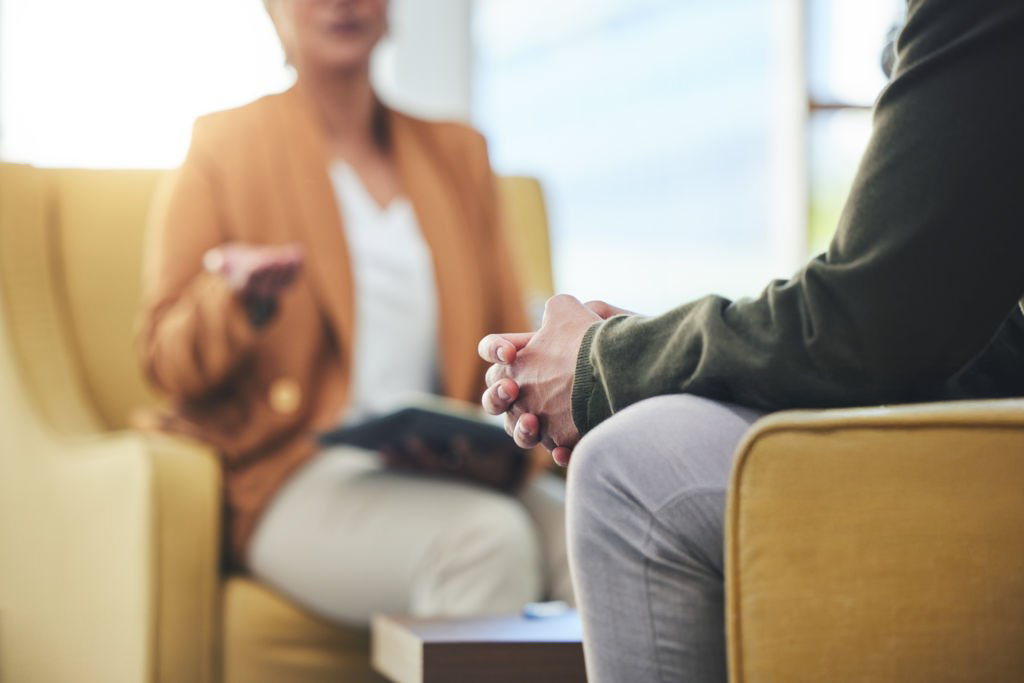 Two people engaged in a coaching conversation while seated in yellow chairs in a bright, modern setting.